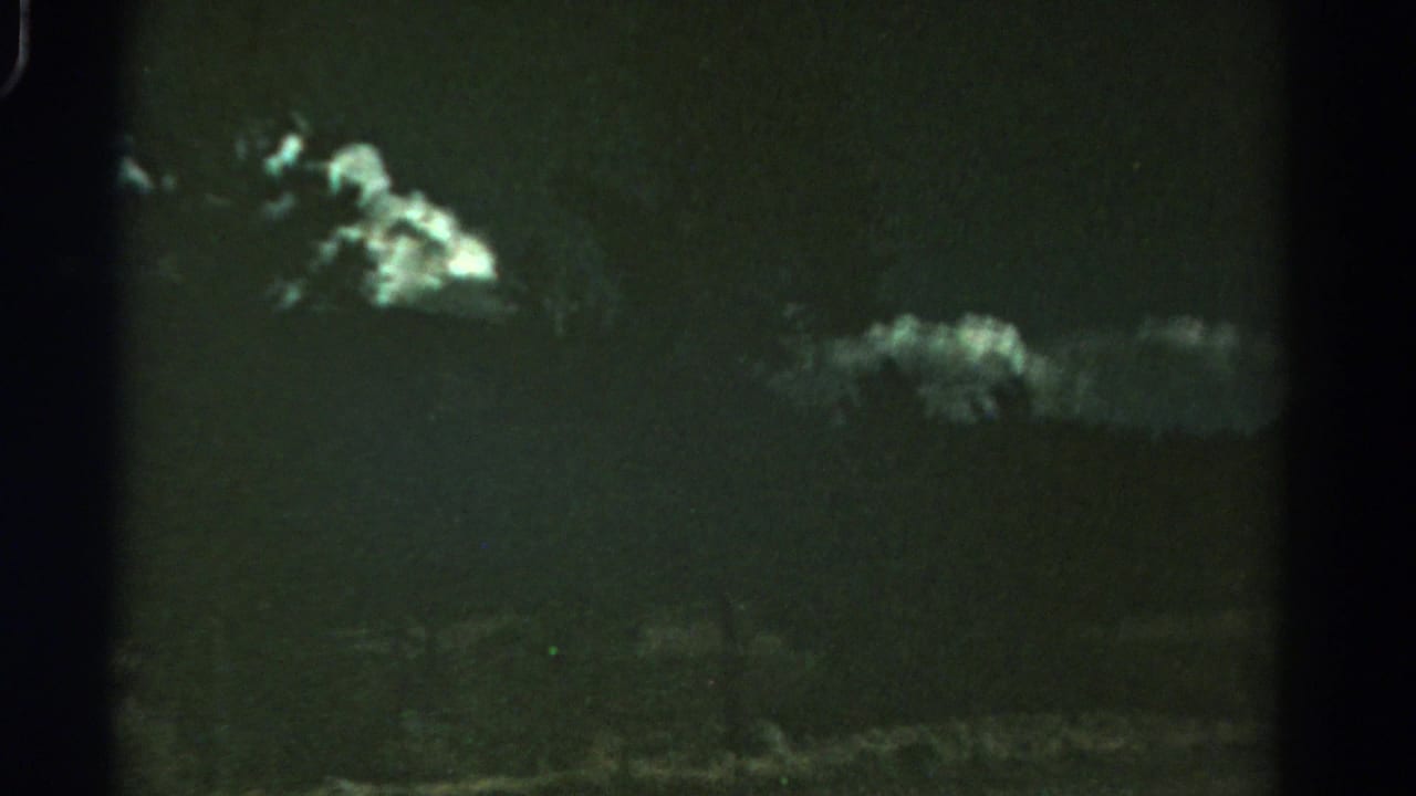 Bright cloud cluster and low cloud band over a dark landscape.