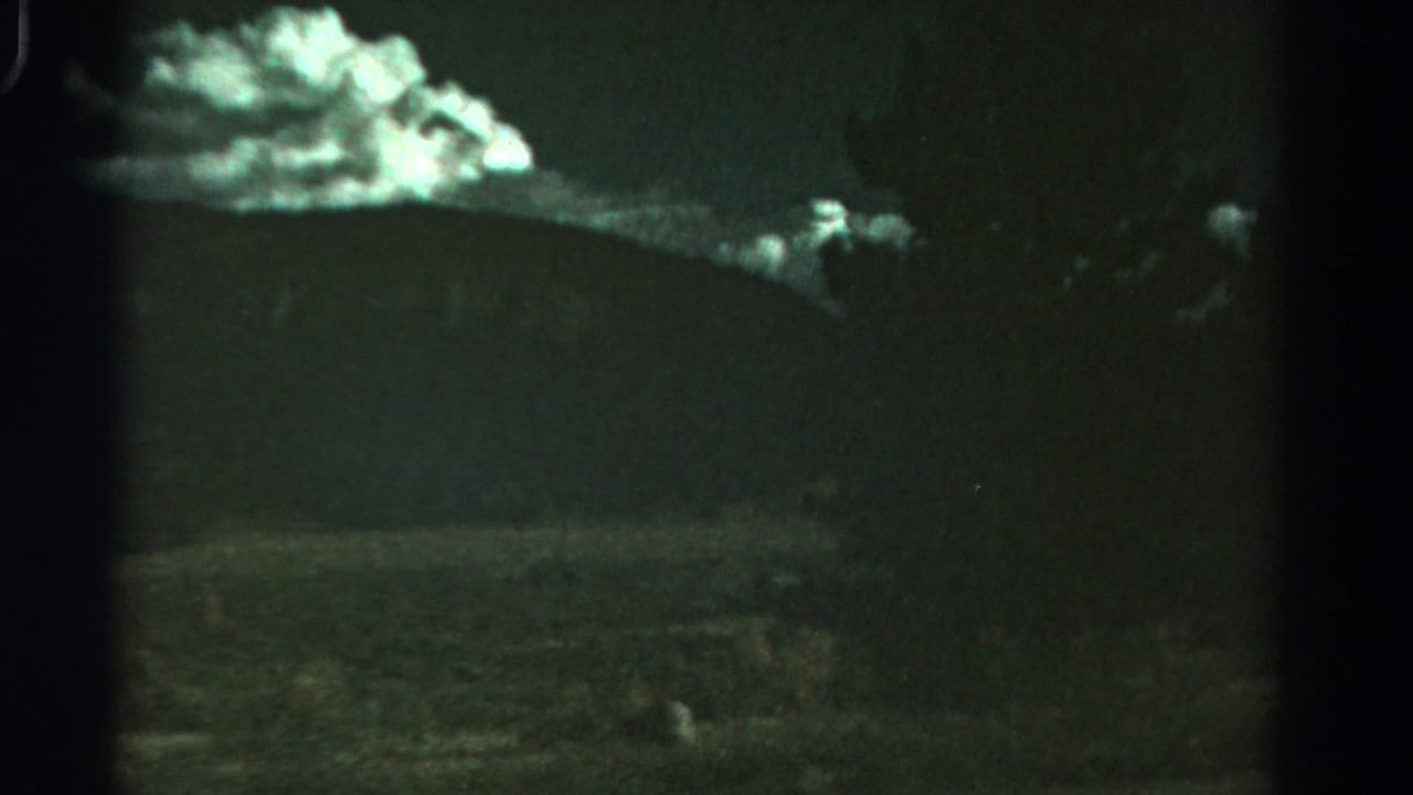 Glowing clouds over dark hills with a faint rural foreground and central film divider.