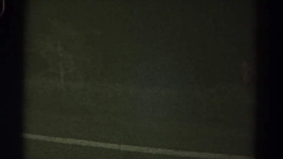 Final 1967 Colorado 8mm frame is mostly dark, with a faint road or ground surface and visible film borders as the shot ends.
