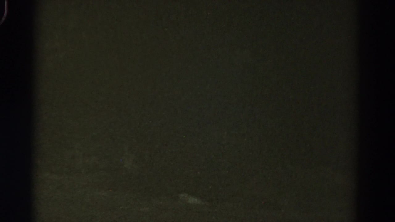 Very dark roadway with a small pale streak near the right side of the frame.