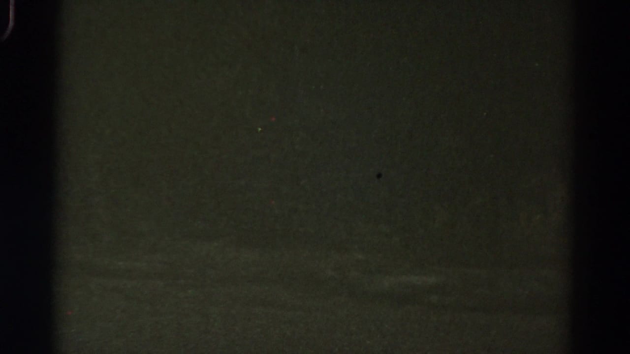 1967 Colorado 8mm frame showing an underexposed nighttime roadside view with dark vertical bars and indistinct green-black shapes.