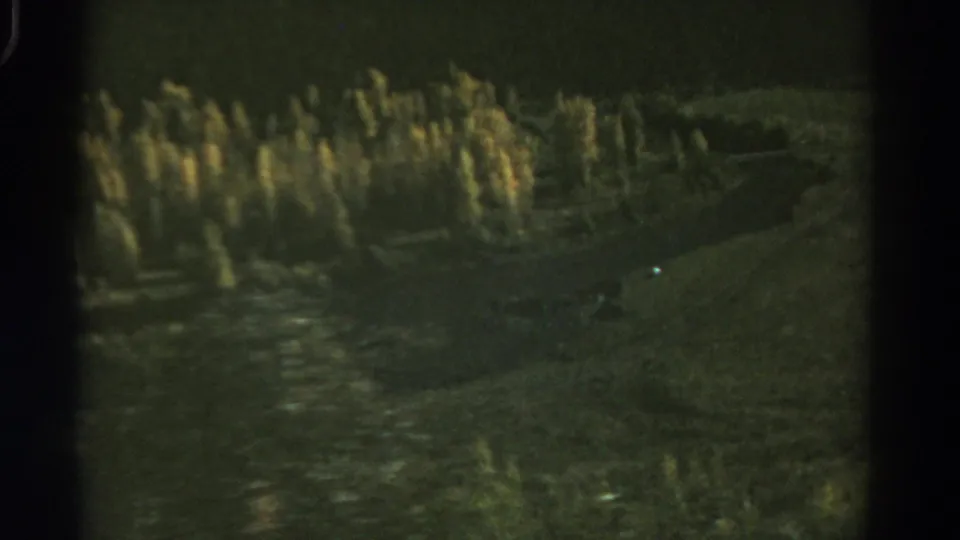 Green-tinted 1967 Colorado 8mm frame showing dim valley terrain, clustered trees, and a faint path or stream in the landscape.