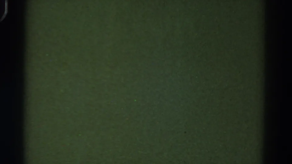 1967 Colorado 8mm frame showing a blank green field, dark frame edges, dust specks, and visible film grain.