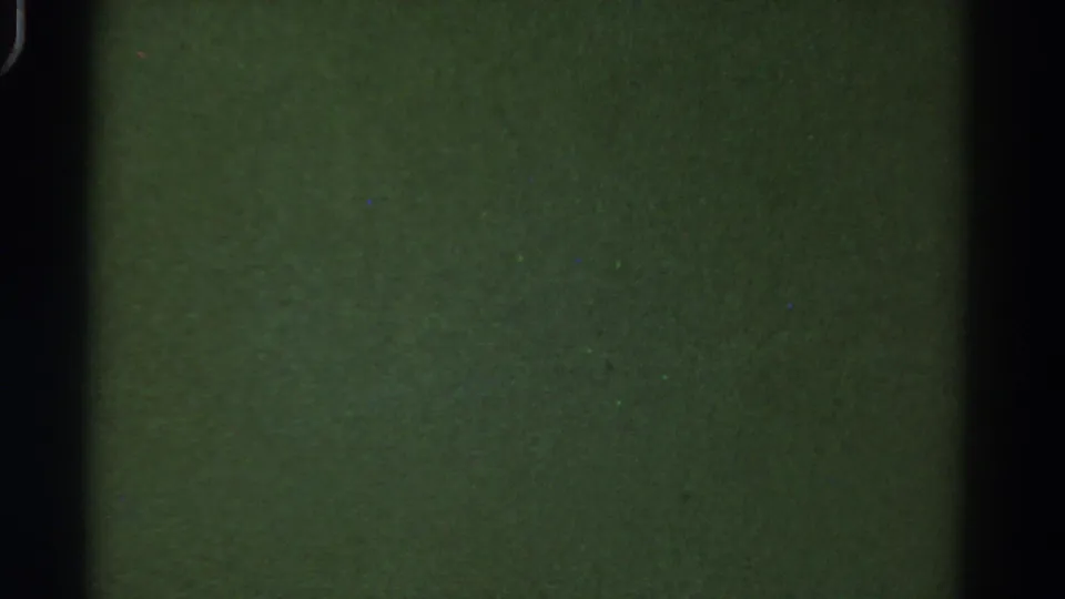 1967 Colorado 8mm frame with a muted green field, strong dark vertical edge, visible grain, and small surface specks.