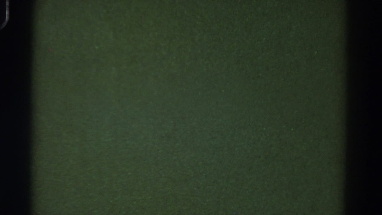 Dark green 8mm blank frame from the 1967 Colorado reel, with black film-gate edges, grain, and small specks.