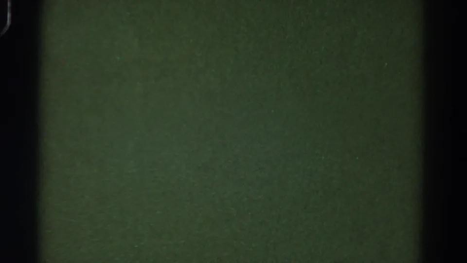 Dark green 8mm blank frame from the 1967 Colorado reel, with black film-gate edges, grain, and small specks.