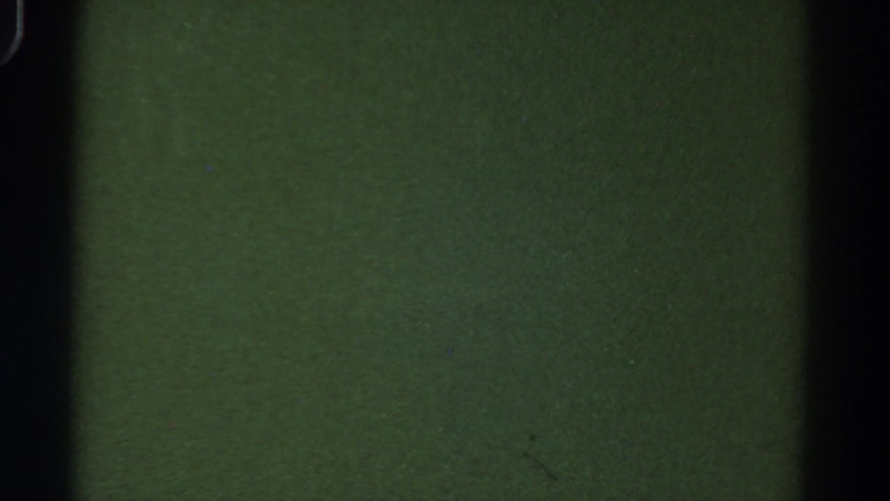 Green-toned blank 8mm frame from the 1967 Colorado reel, crossed by dark frame edges and faint film texture.