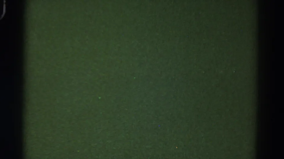 Low-exposure green 8mm frame from the 1967 Colorado reel, showing black gate edge, grain, and slight density shift.
