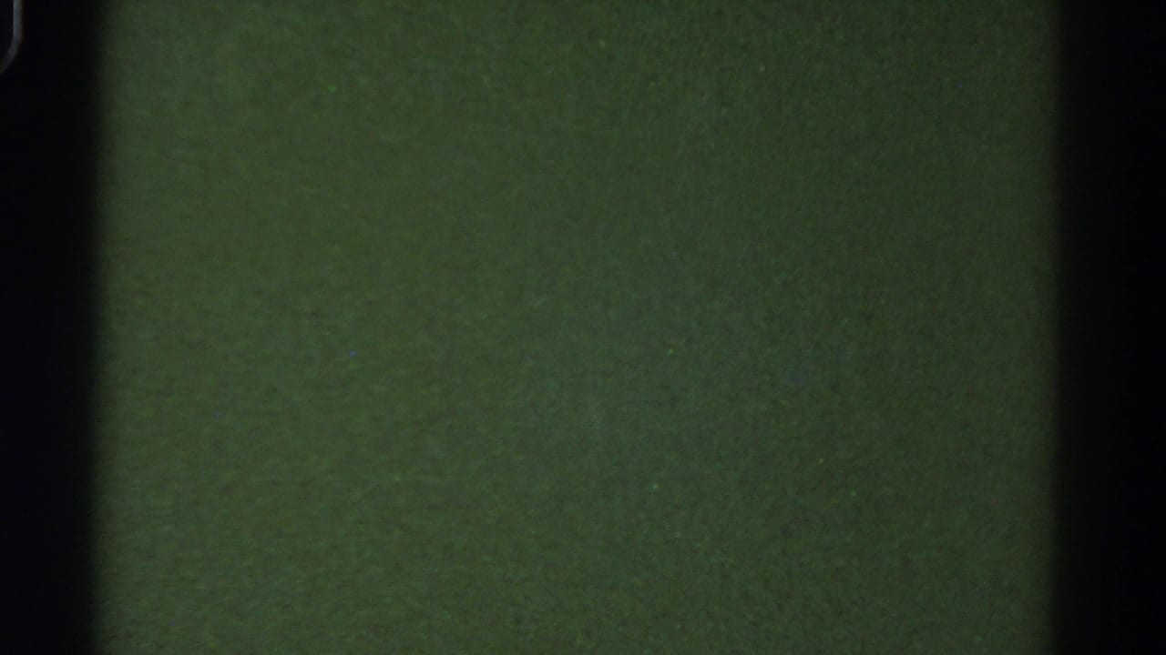Dark 8mm frame from the bus interior in the 1967 Colorado clip, with green-toned surfaces and vertical shadows.