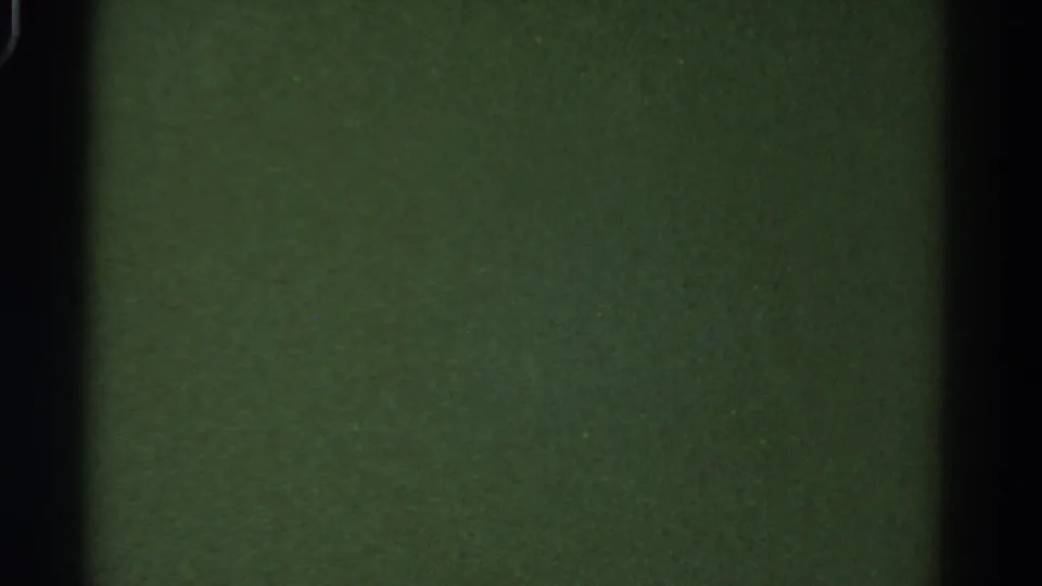 Dark 8mm frame from the bus interior in the 1967 Colorado clip, with green-toned surfaces and vertical shadows.