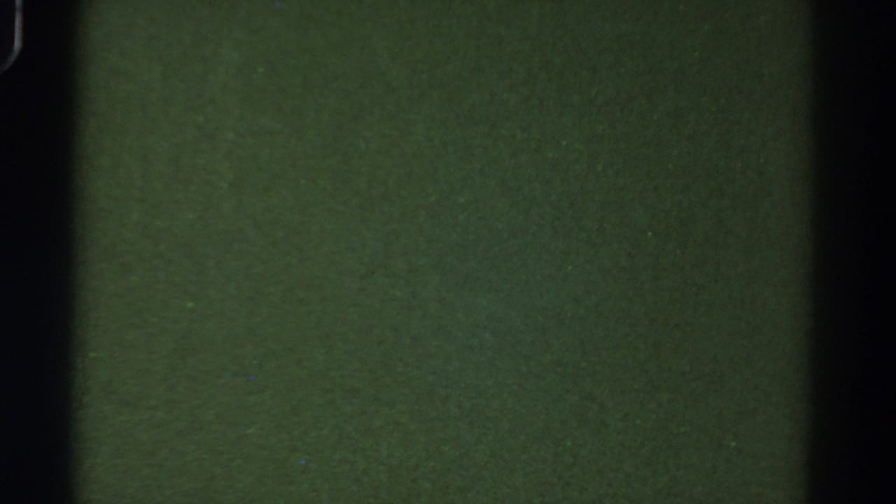 A low-exposure 8mm view inside the bus, showing green-toned interior surfaces and dark vertical framing.