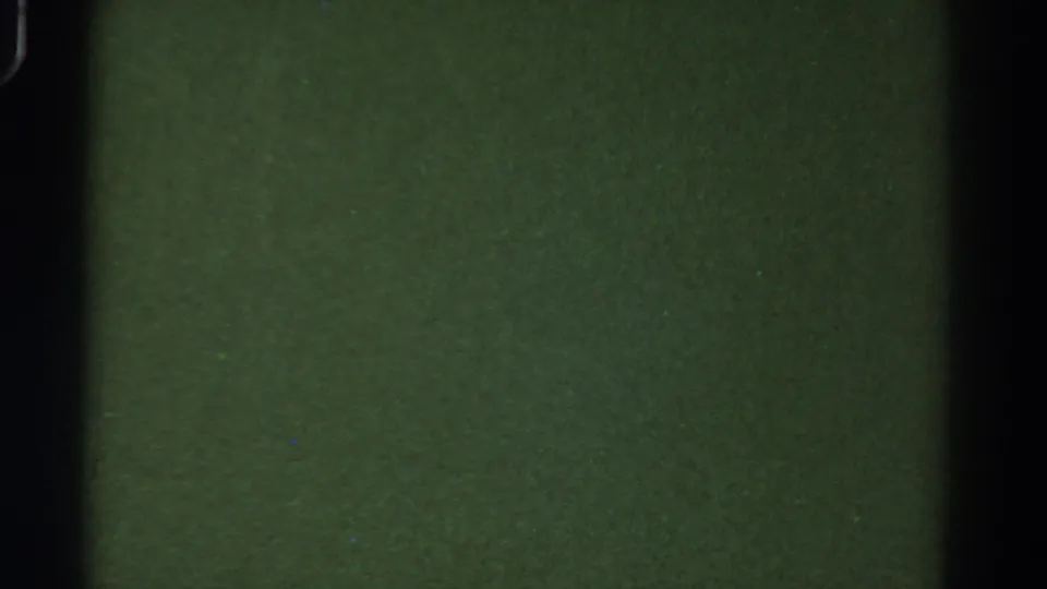A low-exposure 8mm view inside the bus, showing green-toned interior surfaces and dark vertical framing.