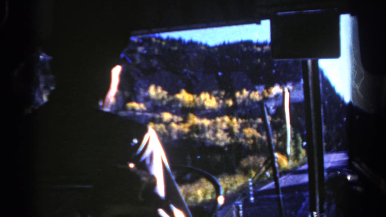 1967 Colorado 8mm bus interior view looking through the windshield toward autumn trees, road, and hillside.