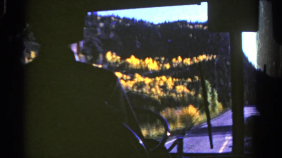 1967 Colorado travel footage shows a bus windshield framing golden autumn trees and a forested hillside.