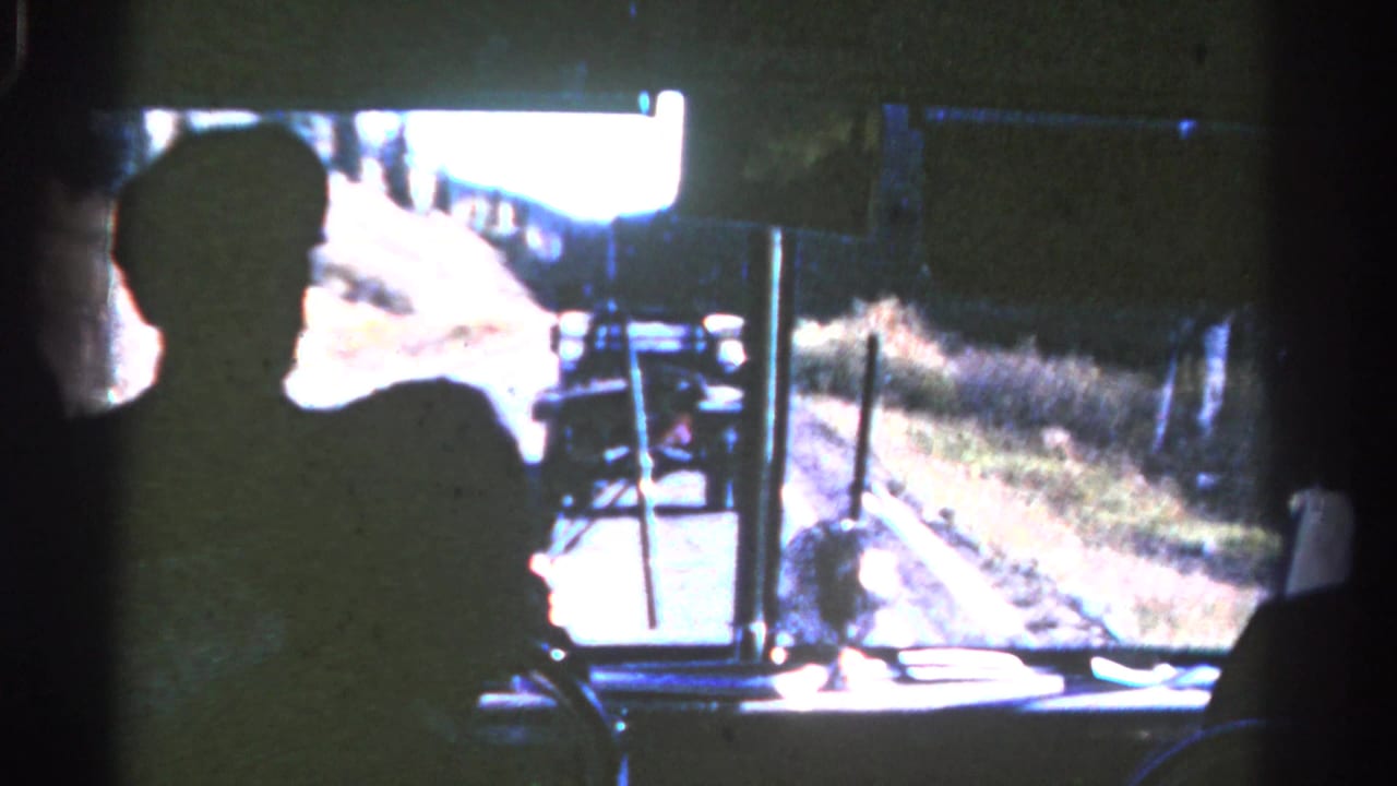 Silhouetted passenger looks forward through a bus windshield at a truck on the road.
