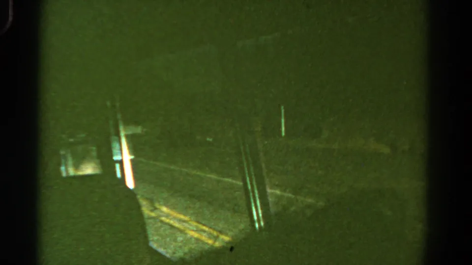 Passenger view of a nighttime Colorado road through a vehicle window, with yellow lane markings, roadside posts, and dense darkness beyond.
