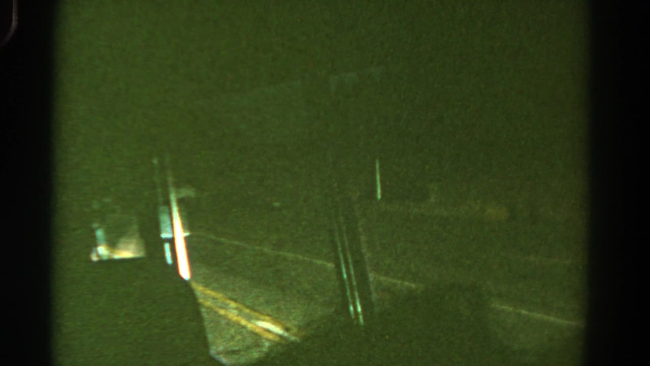 1967 Colorado 8mm frame showing a dim night road from inside a moving vehicle, with green tint, blur, and black film borders.