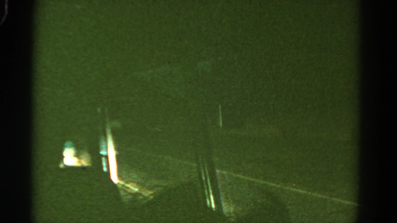 Blurred night road with roadside lights and dark vertical film borders.