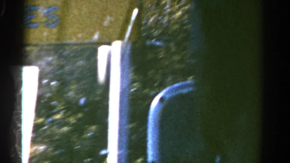 A passing roadside object or sign edge fills the 1967 Colorado home-movie frame, with bright overexposure and heavy motion blur.