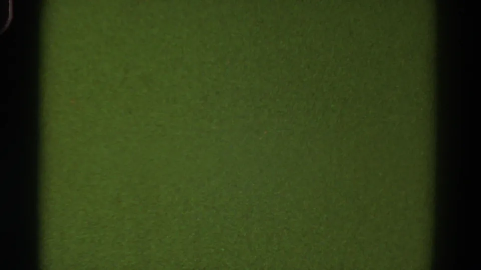 Final 1967 Colorado 8mm frame showing green roadside texture through a dark car-window edge.