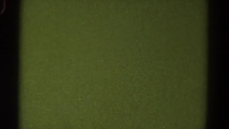 1967 Colorado 8mm frame presenting a muted green field with a dark vertical border, rounded gate edge, and fine film grain.