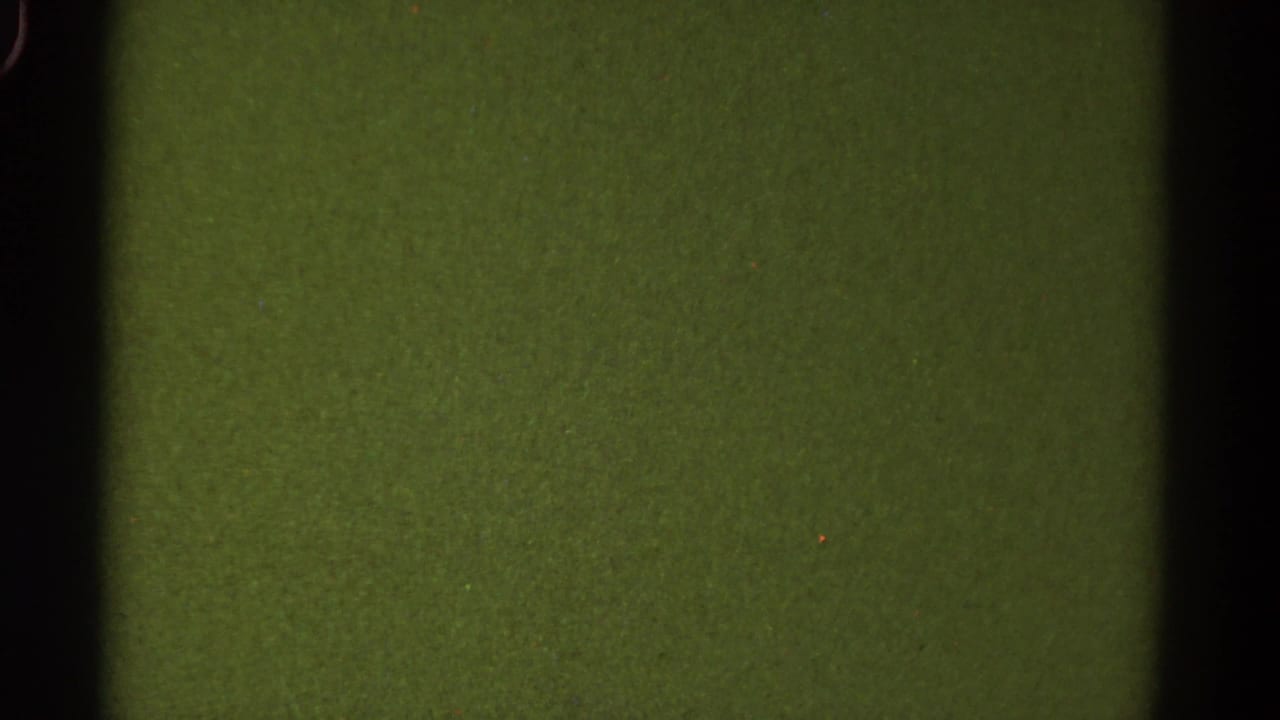 1967 Colorado 8mm frame showing a blank green-tinted film area with dark gate bars, grain, dust specks, and soft rounded edges.