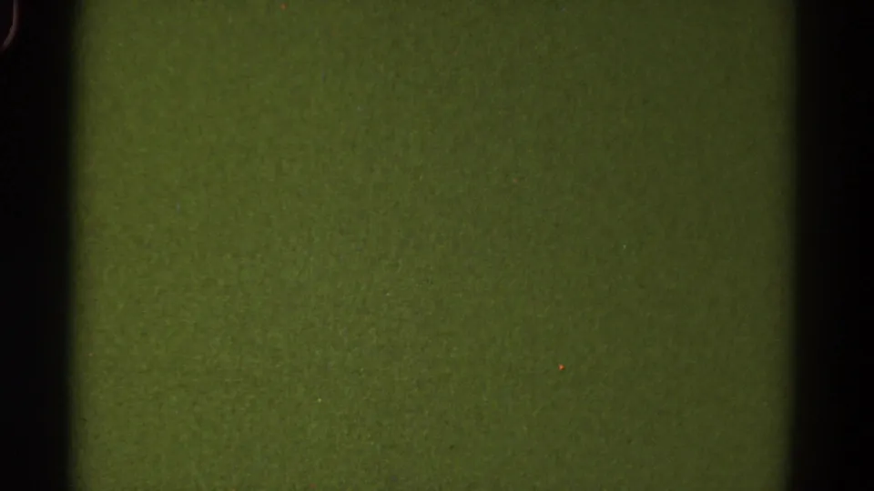 1967 Colorado 8mm frame showing a blank green-tinted film area with dark gate bars, grain, dust specks, and soft rounded edges.