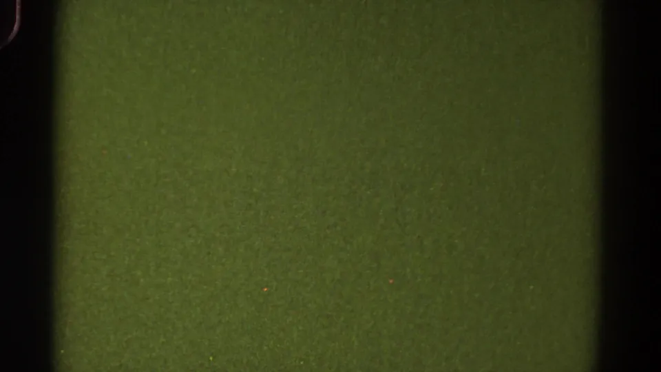 1967 Colorado 8mm still with a green blank field, black vertical frame edges, visible grain, scattered specks, and slight exposure variation.