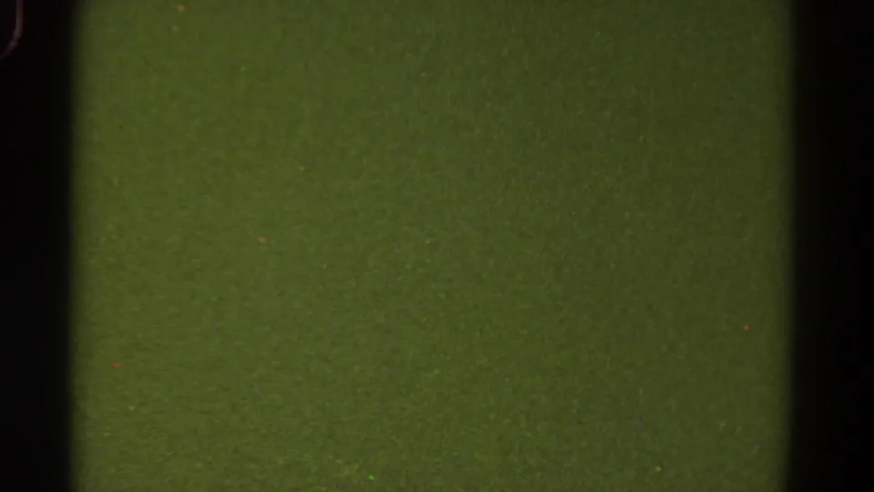 1967 Colorado 8mm frame showing a green film surface, dark gate bars, dust specks, heavy grain, and a horizontal exposure shift.