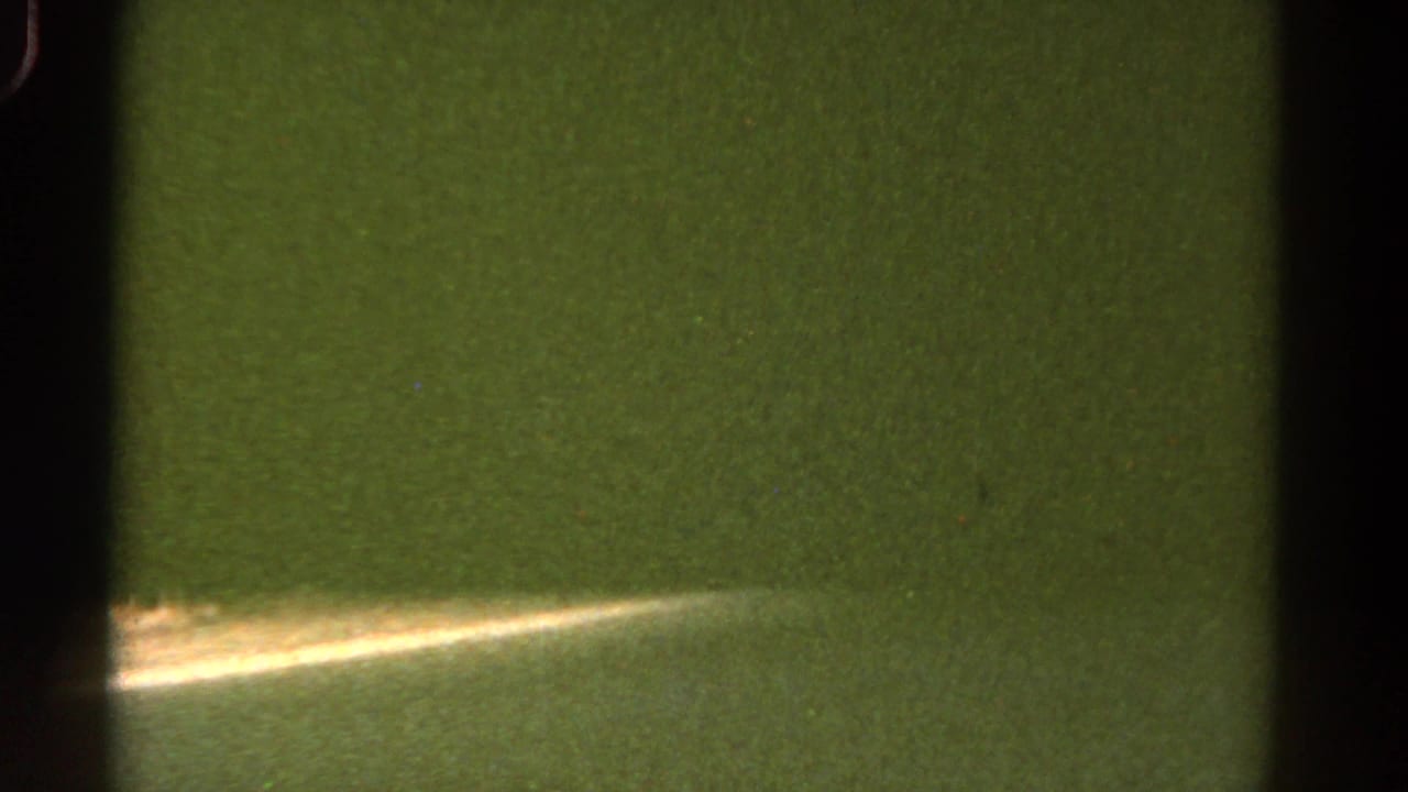 1967 Colorado 8mm frame showing a green-tinted road edge, soft vegetation, and heavy film grain.