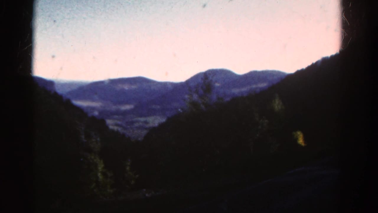 Distant mountain ridges seen between dark forested slopes.