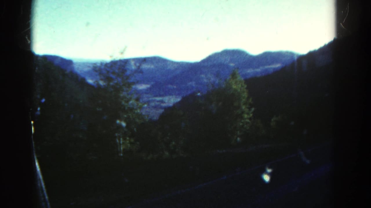 Distant mountains and a valley framed by a dark window edge.