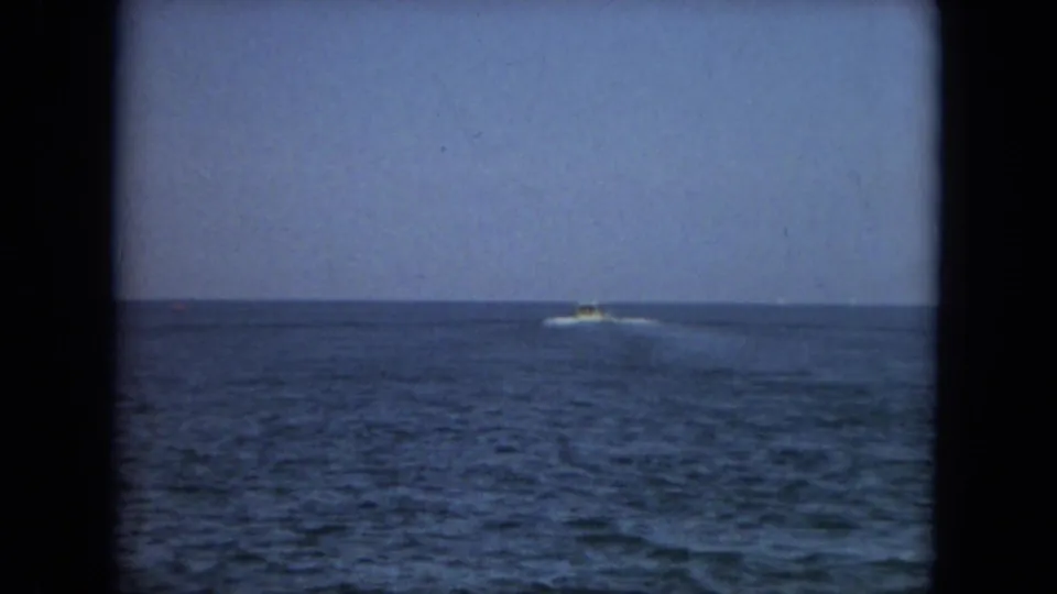 A distant boat moves along the horizon on blue coastal water in this Florida home-movie frame from 1967.