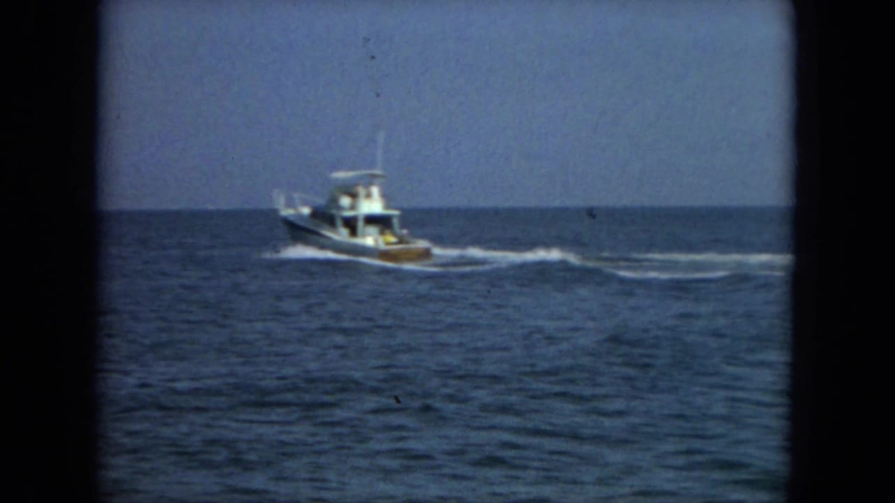 Small motorboat cruising over open water with a white wake behind it.