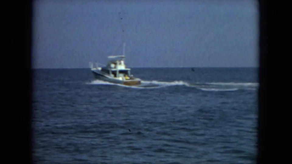 1967 Florida coastal 8mm frame with a small motorboat moving across blue sea under a clear sky.