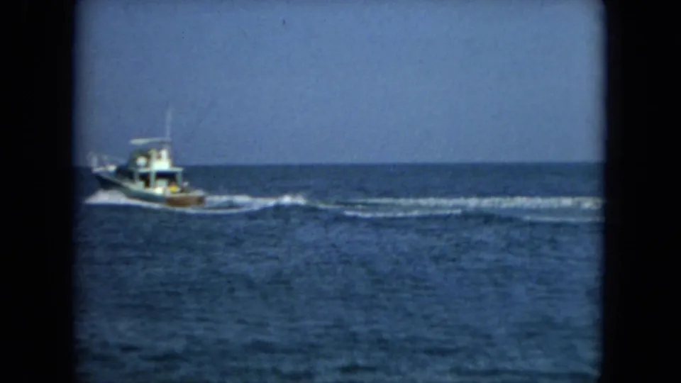 1967 Florida home-movie frame showing a motorboat crossing open coastal water with its wake trailing behind.