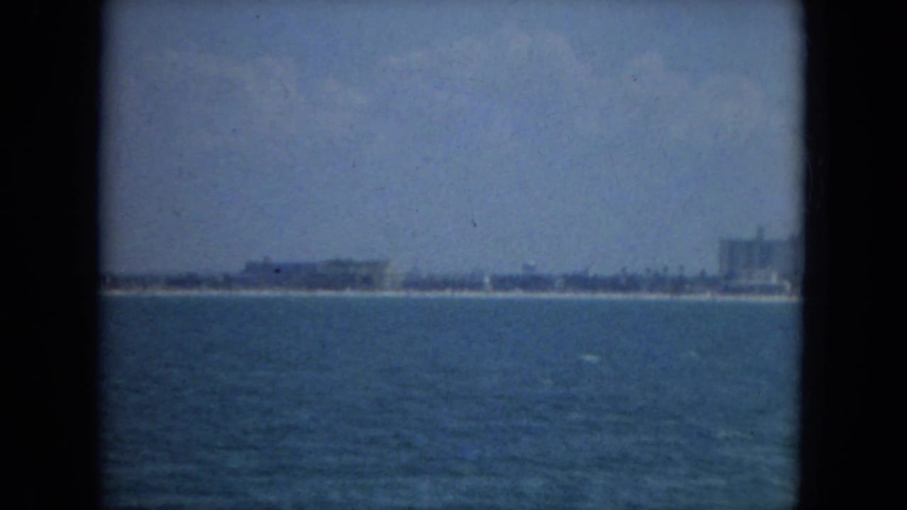 1967 Florida 8mm frame showing open blue water with a low distant shoreline under a hazy sky.