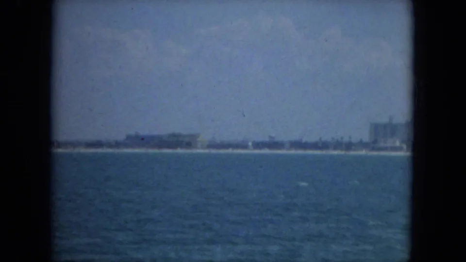 1967 Florida 8mm frame showing open blue water with a low distant shoreline under a hazy sky.