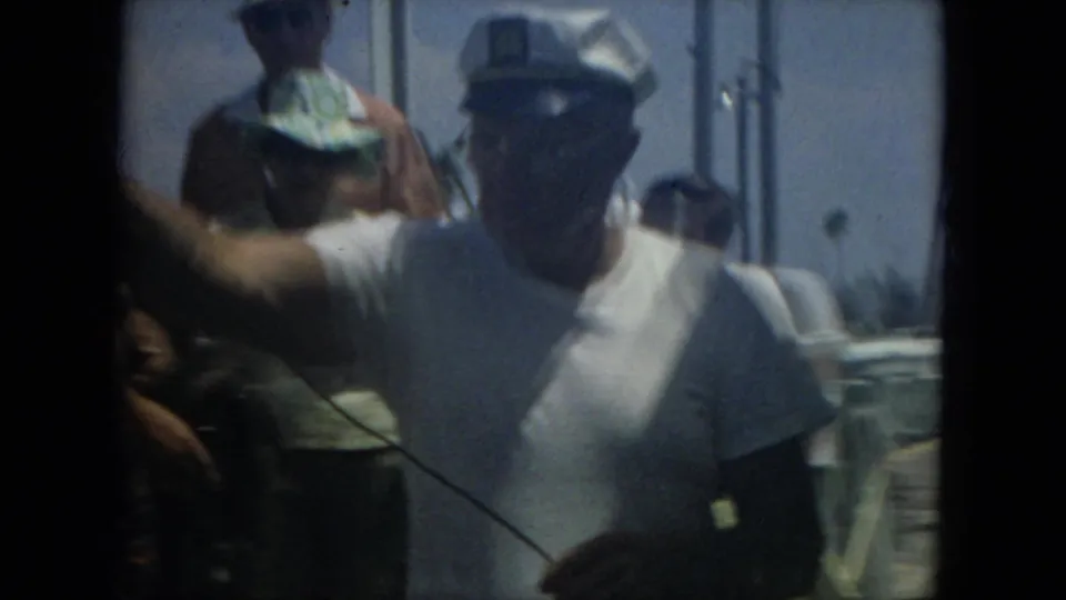 Passengers aboard a 1967 Florida boat ride, including a man in a white shirt and hat, filmed through dark 8mm frame edges.