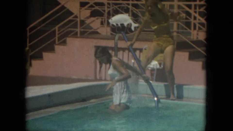 A woman in a yellow swimsuit holds a pool skimmer as another woman in white kneels in the Florida pool in 1967.