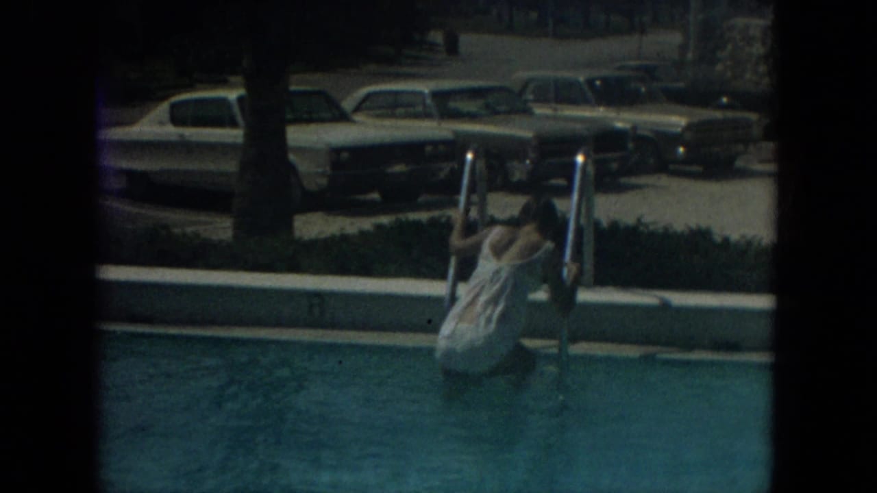 A woman at a pool ladder appears in front of parked mid-century cars and palm shade in Florida in 1967.