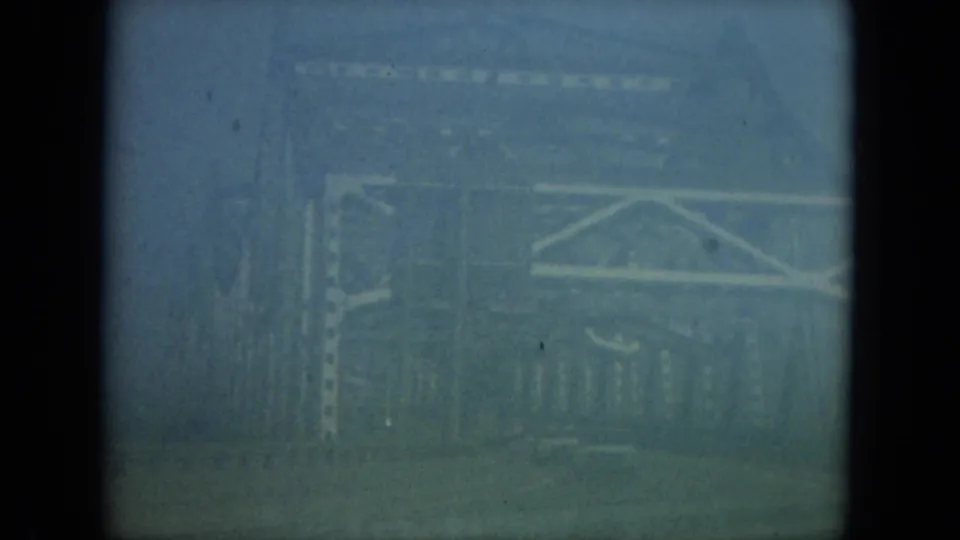 1967 Florida 8mm frame looking through a dark car window toward hazy bridge-like railings and exterior structure.
