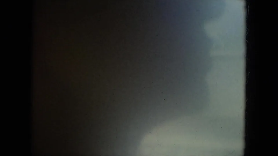 1967 Florida home-movie frame with a dark silhouette near the car window and indistinct light outside.