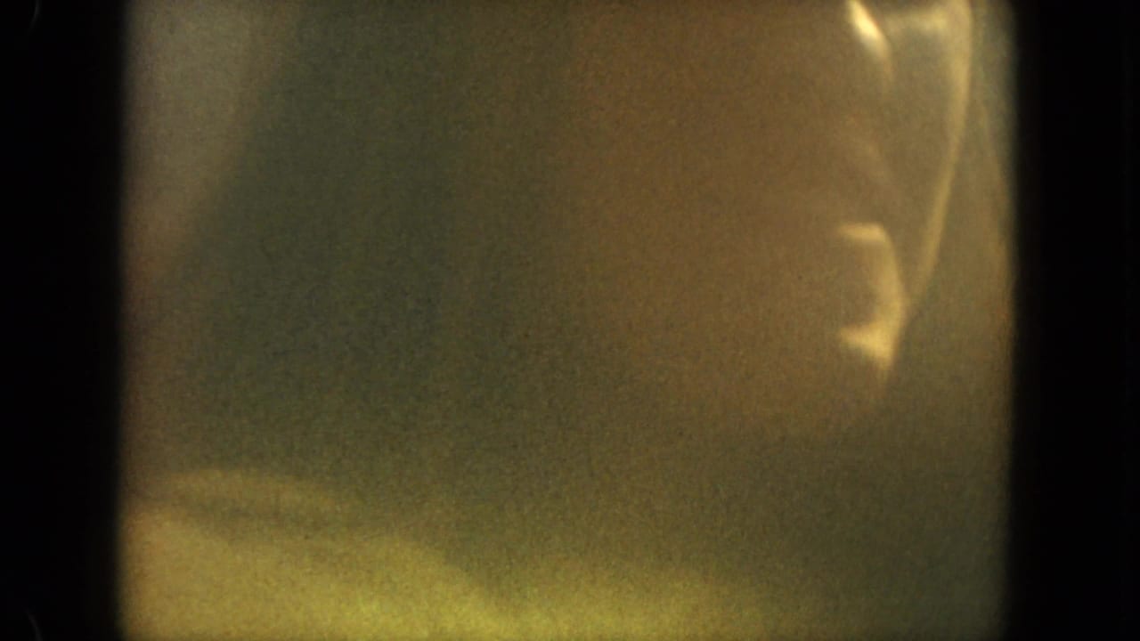 Partial face of a woman near the right edge of a grainy frame.