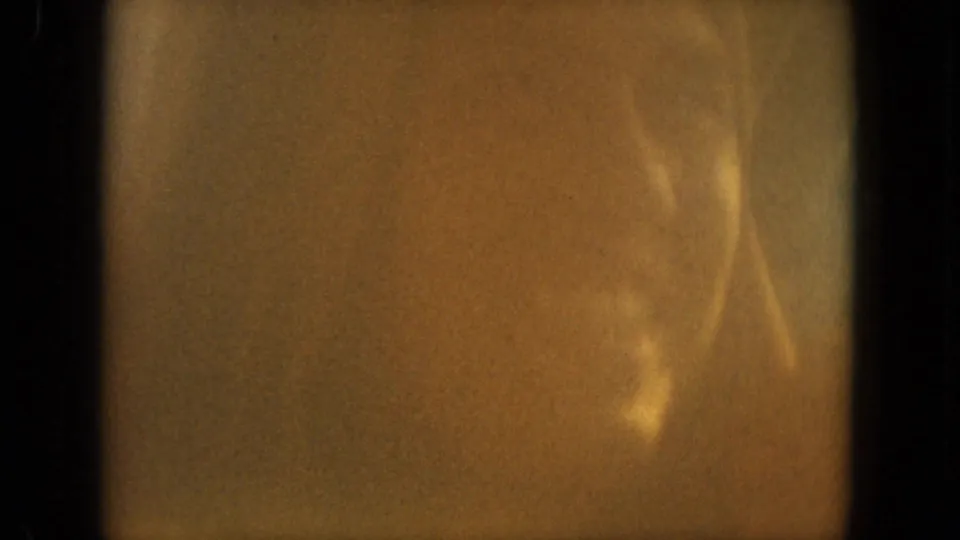 A blurred close-up shows faint facial features and warm film flare in the 1967 Florida home-movie clip.