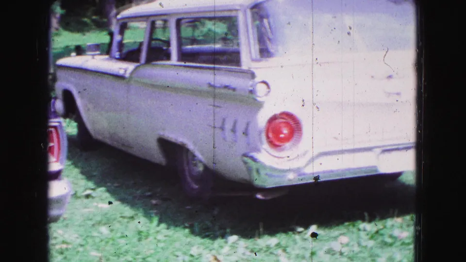 White 1960s station wagon seen from the rear side in 1967 Galena, Illinois home-movie footage.