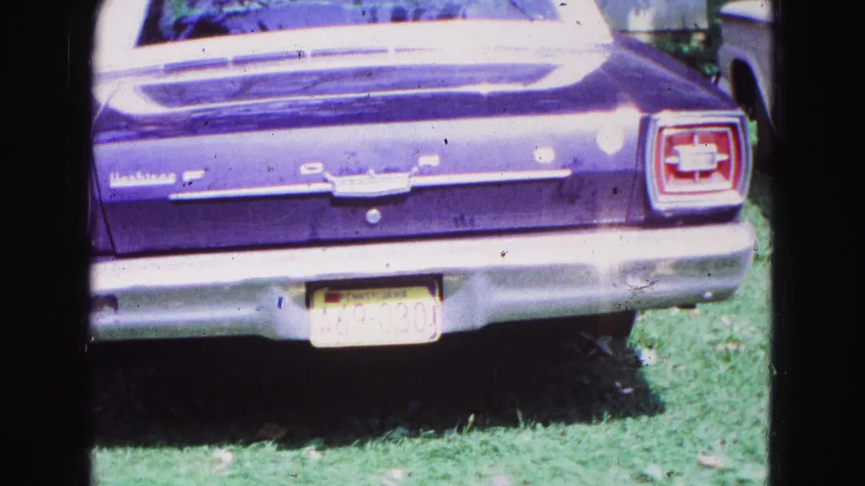 Rear view of a purple Ford Falcon with visible badging, taillights, bumper, and license plate in 1967 Galena, Illinois footage.