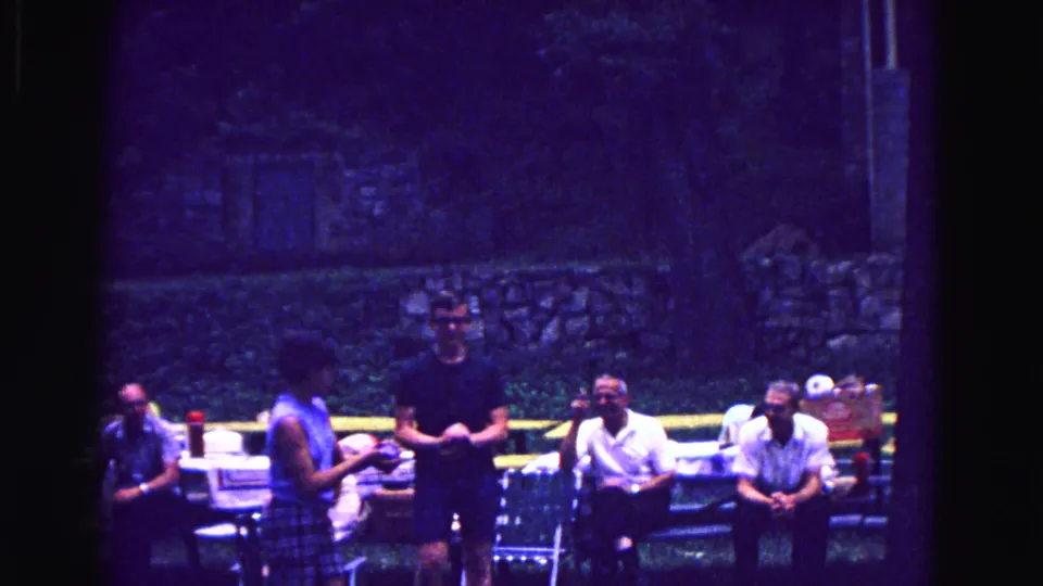 A shaded picnic area with adults at tables appears in this 1967 Galena, Illinois family reunion home movie.