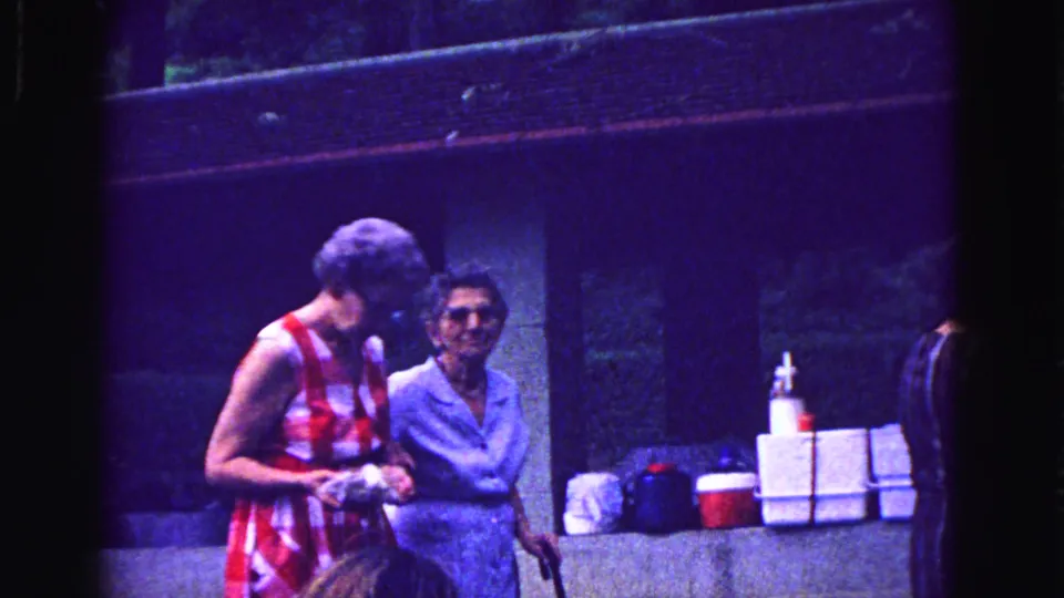 In the final 1967 Galena frame, two elderly women stand together near stacked coolers, with one looking toward the camera.