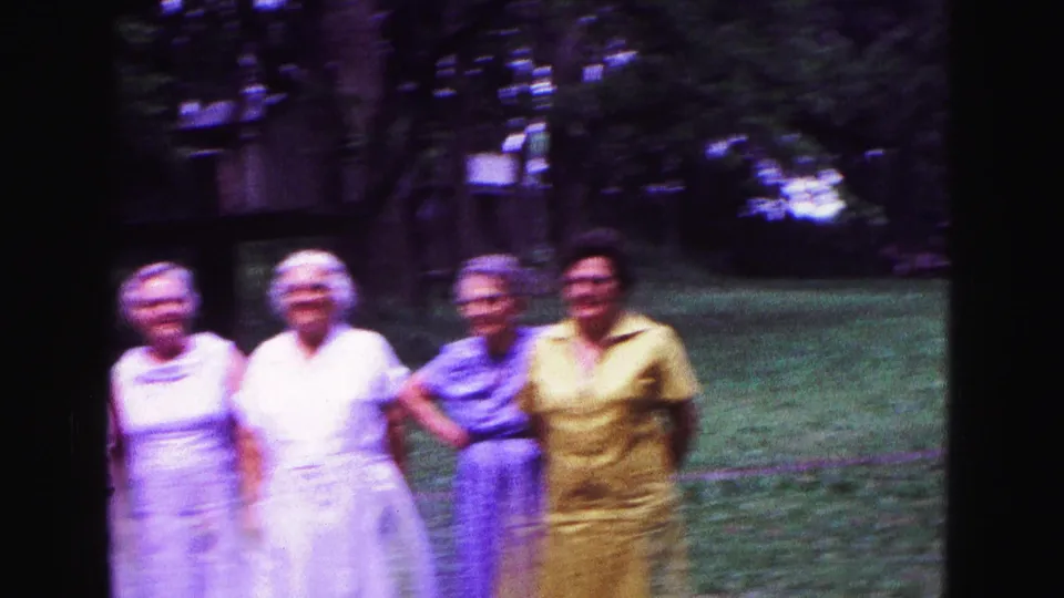 Four adults, including older women and a person in a yellow shirt, stand arm in arm on the lawn during the 1967 Galena picnic.